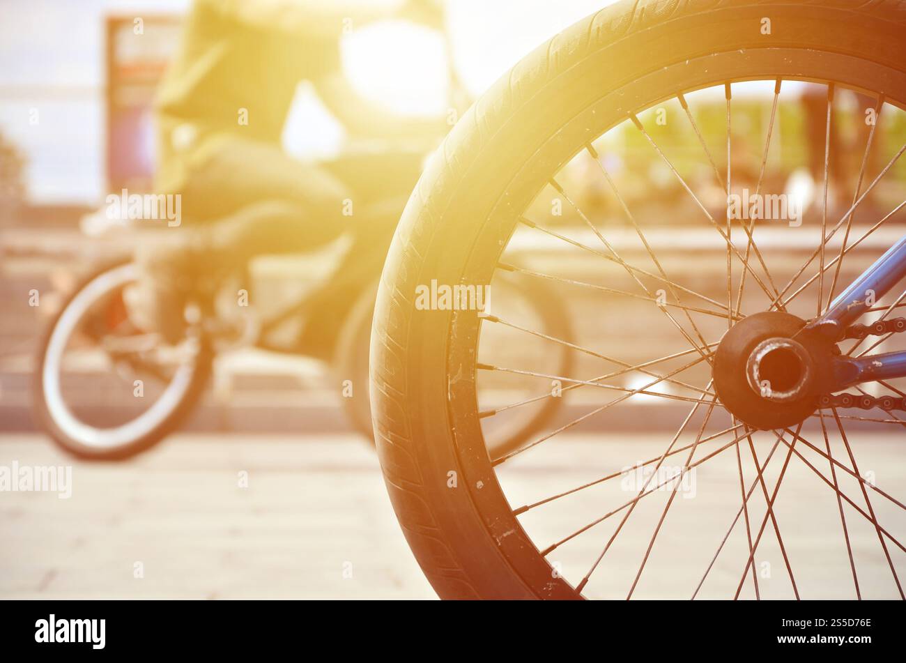 Une roue de vélo BMX dans le contexte d'une rue avec des coureurs cyclistes brouillée. Extreme Sports Concept Banque D'Images Une roue de vélo BMX dans le contexte d'une rue avec des coureurs cyclistes brouillée. Extreme Sports Concept Banque D'Images