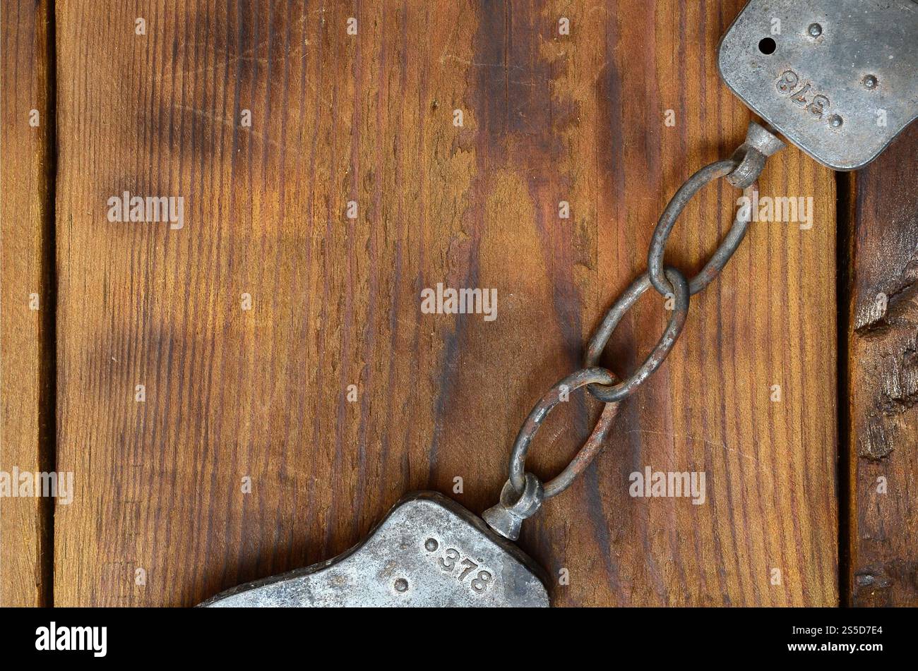 Les menottes de police vieilles et rouillées reposent sur une surface en bois rayée. Le concept d'un vieux crime Banque D'Images