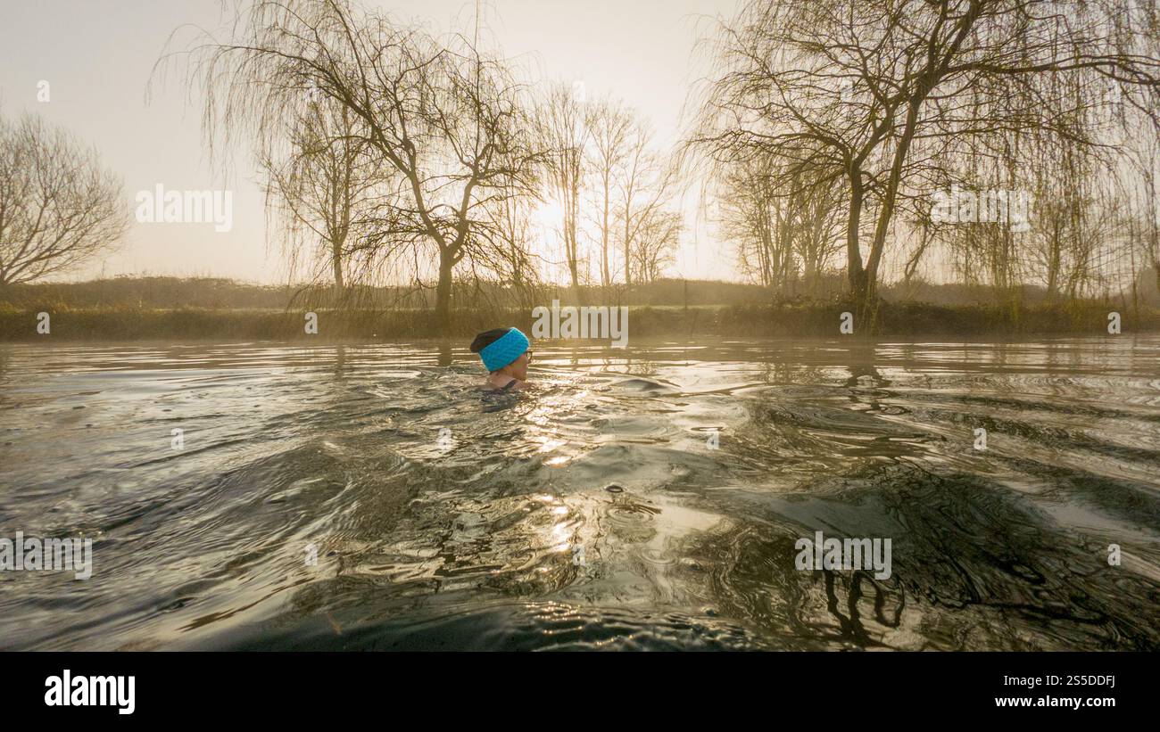 Femme solitaire Wild nageant à la première lumière un jour d'hiver froid et brumeux. ROYAUME-UNI Banque D'Images