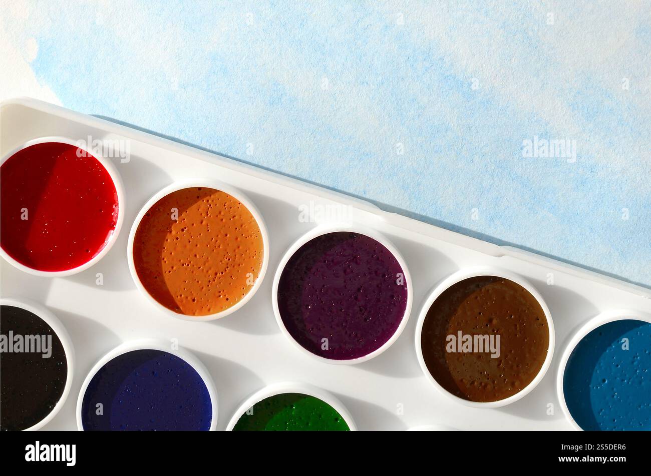 Un nouvel ensemble d'aquarelles repose sur une feuille de papier, qui montre un dessin abstrait d'aquarelle sous la forme de traits bleus. Le concept d'amateur Banque D'Images