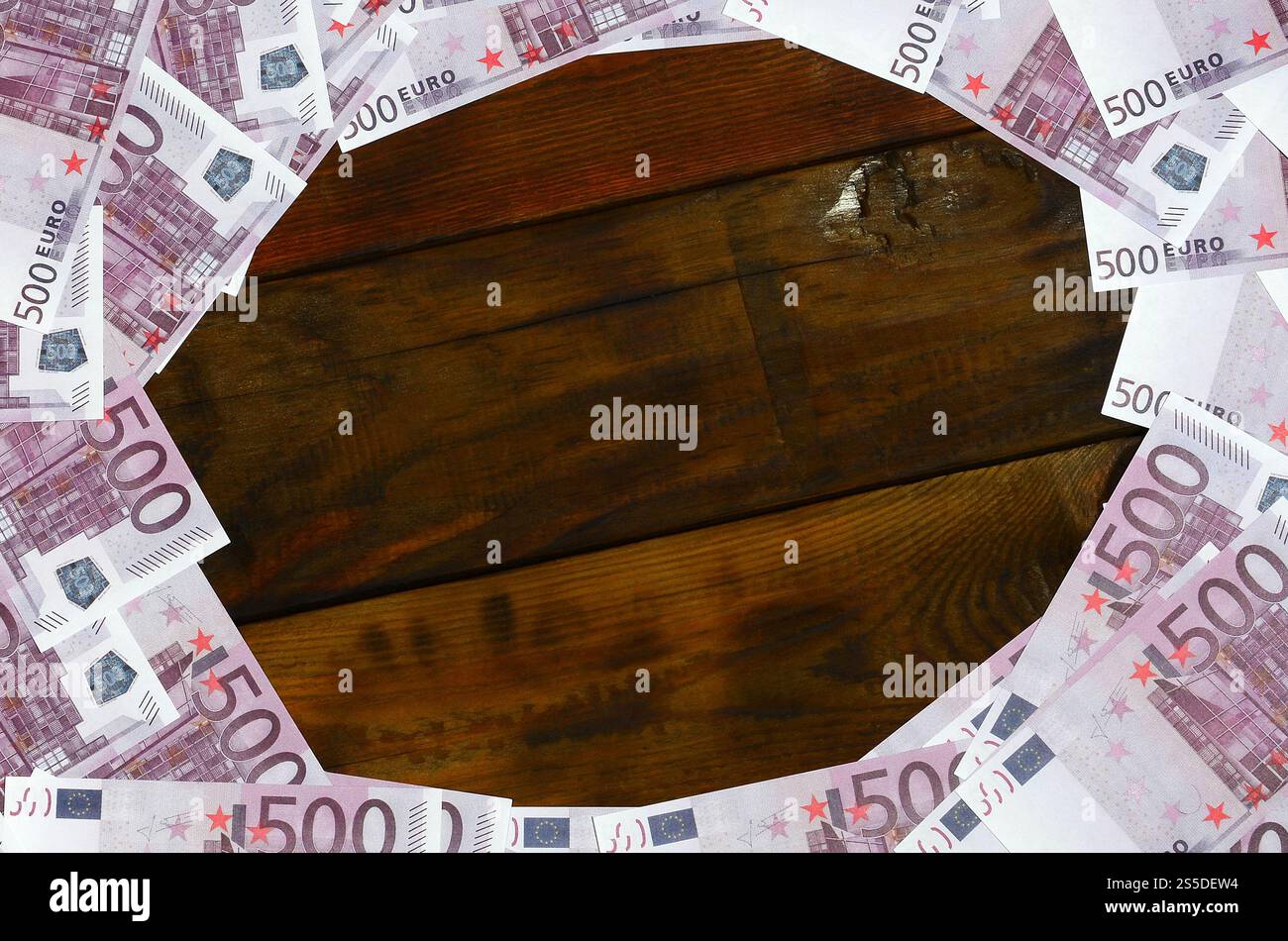 Beaucoup de dénominations pourpres d'une valeur de 500 euros se trouvent sur une surface en bois avec un bloc vide au milieu de l'image. Copier l'espace pour le texte Banque D'Images