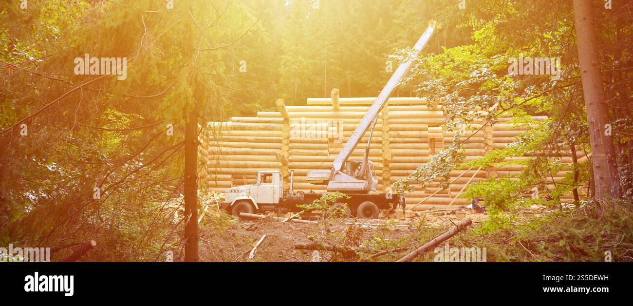 Le processus de construction d'une maison en bois à partir de poutres en bois de forme cylindrique. Grue en état de fonctionnement Banque D'Images