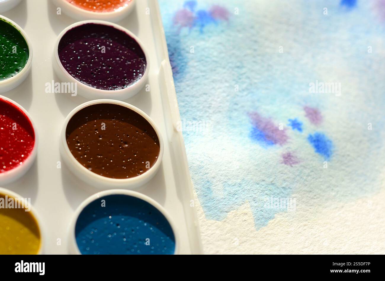 Un nouvel ensemble d'aquarelles repose sur une feuille de papier, qui montre un dessin abstrait d'aquarelle sous la forme de traits bleus. Le concept d'amateur Banque D'Images