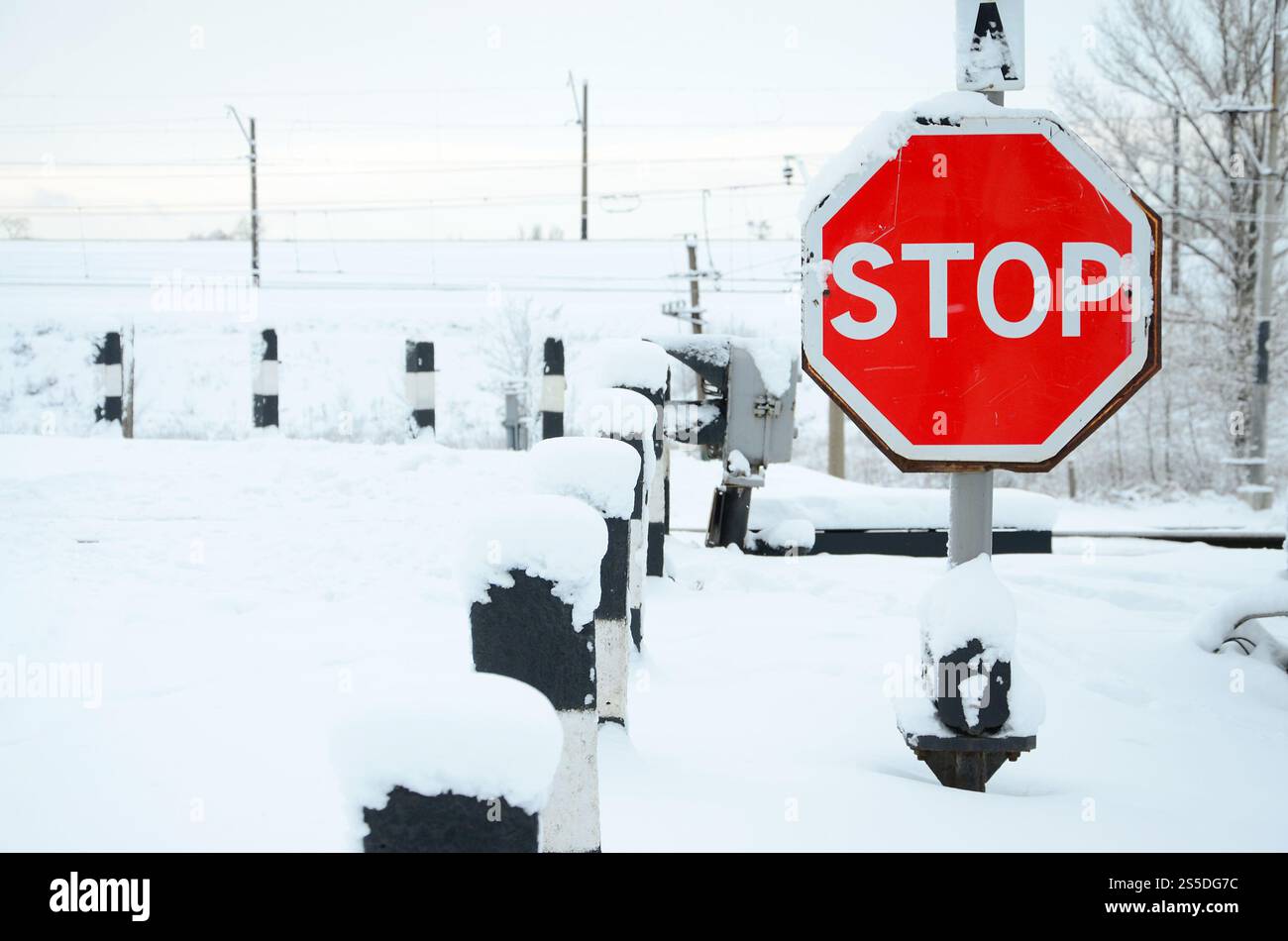Arrêter. Le panneau rouge est situé sur l'autoroute qui traverse la ligne de chemin de fer en hiver Banque D'Images
