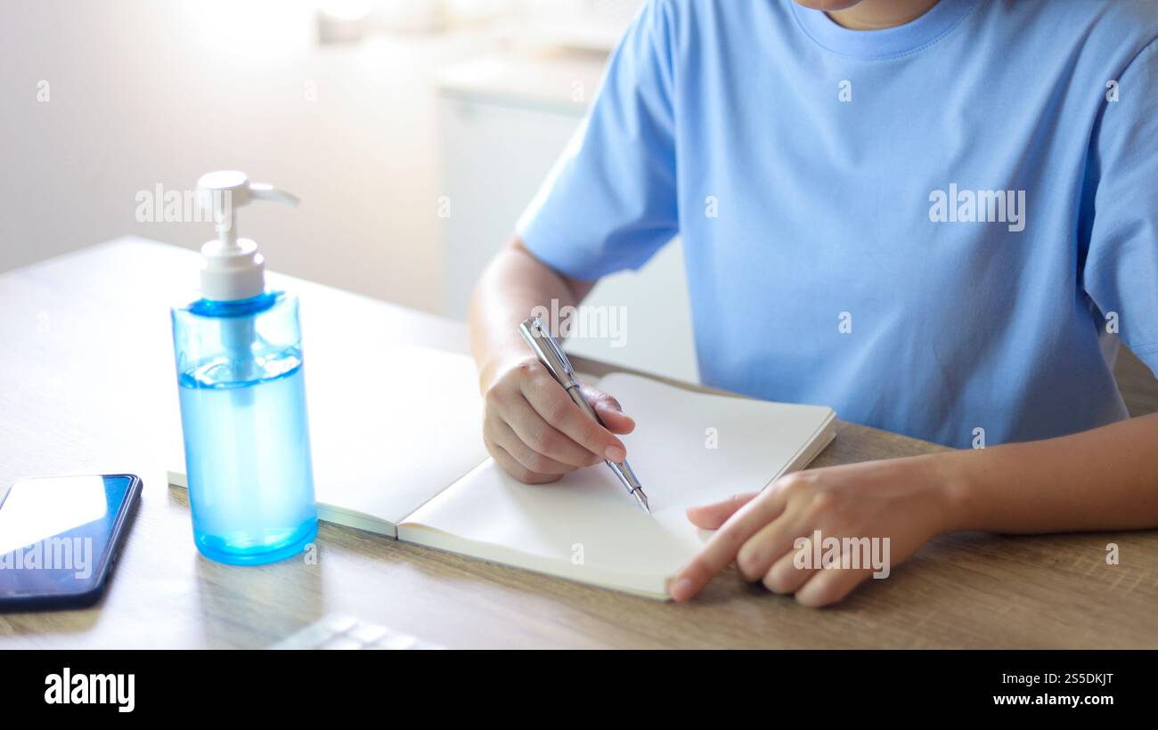Jeune femme asiatique portant le masque médical fait à la main du visage travaillant seule politique de distanciation avec. Gel désinfectant pour les mains pendant le coronavirus ou le virus covid-19 Banque D'Images