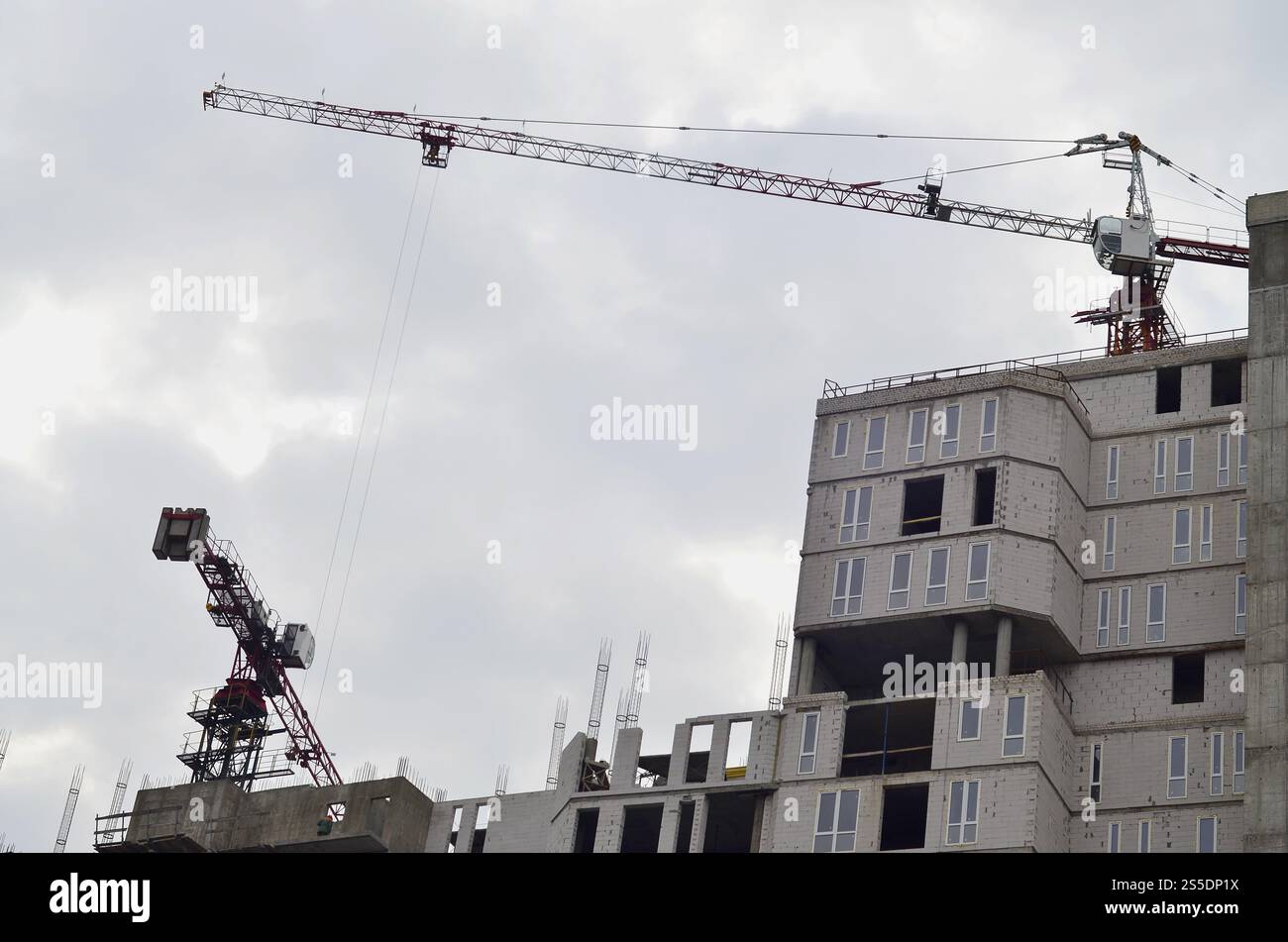 Grues hautes de travail à l'intérieur de l'endroit pour avec des bâtiments hauts en construction contre un ciel bleu clair. Grue et construction progression du travail avec Banque D'Images
