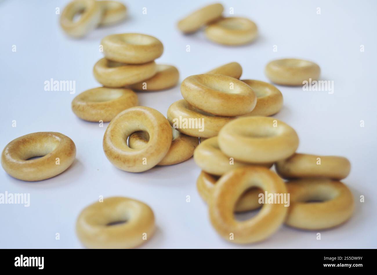 Petit tas de bagels dorés sur surface blanche. Macrophotographie. Bagels ronds jaunes Banque D'Images Petit tas de bagels dorés sur surface blanche. Macrophotographie. Bagels ronds jaunes Banque D'Images
