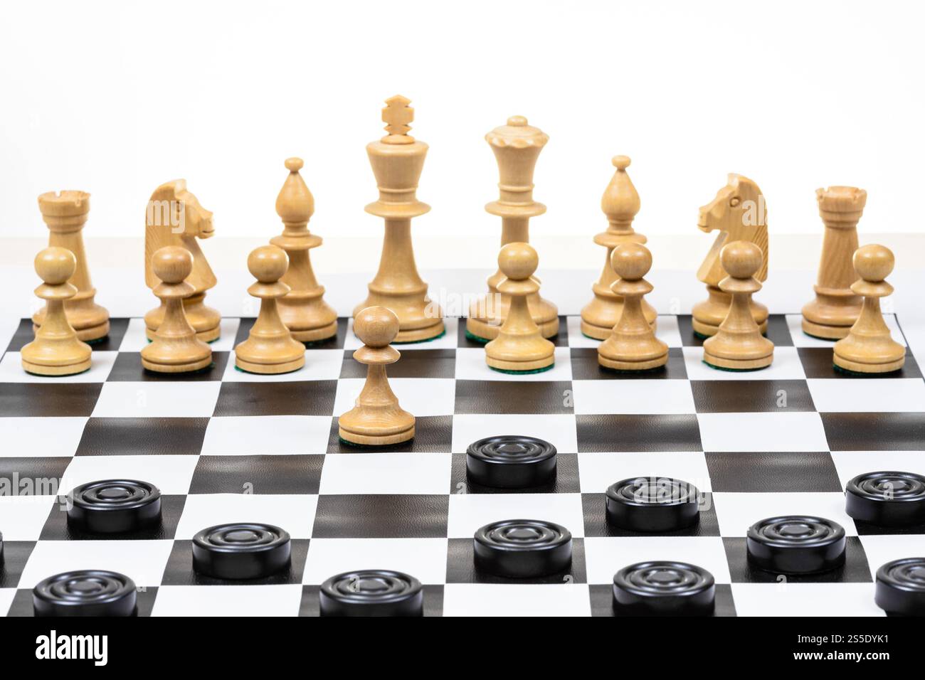 jouer par différentes règles sur le même plateau - les dames noires et les figures d'échecs blanches sur échiquier noir blanc, pion et pion de pièce de dames se déplacent (focus Banque D'Images