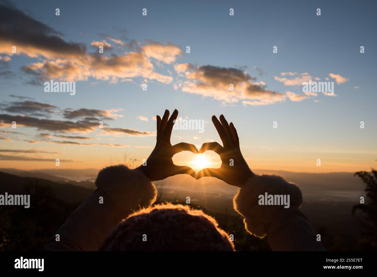 Silhouette des mains formant un coeur avec le lever du soleil Banque D'Images