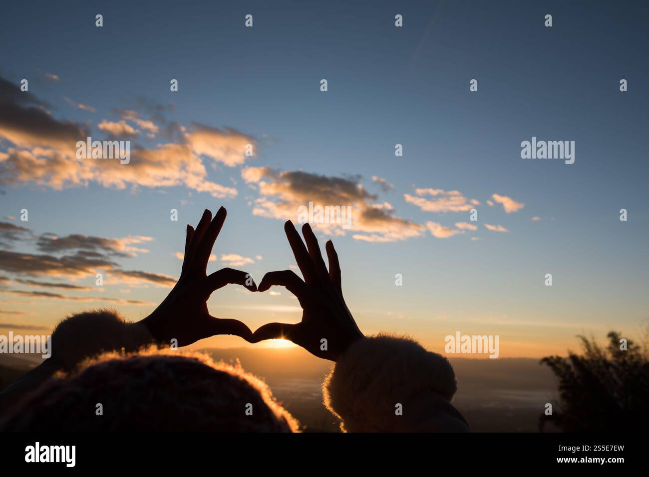 Silhouette des mains formant un coeur avec le lever du soleil Banque D'Images