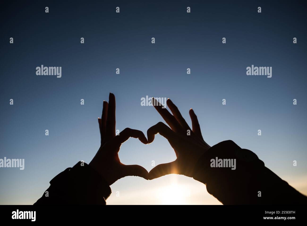 Silhouette des mains formant un coeur avec le lever du soleil Banque D'Images