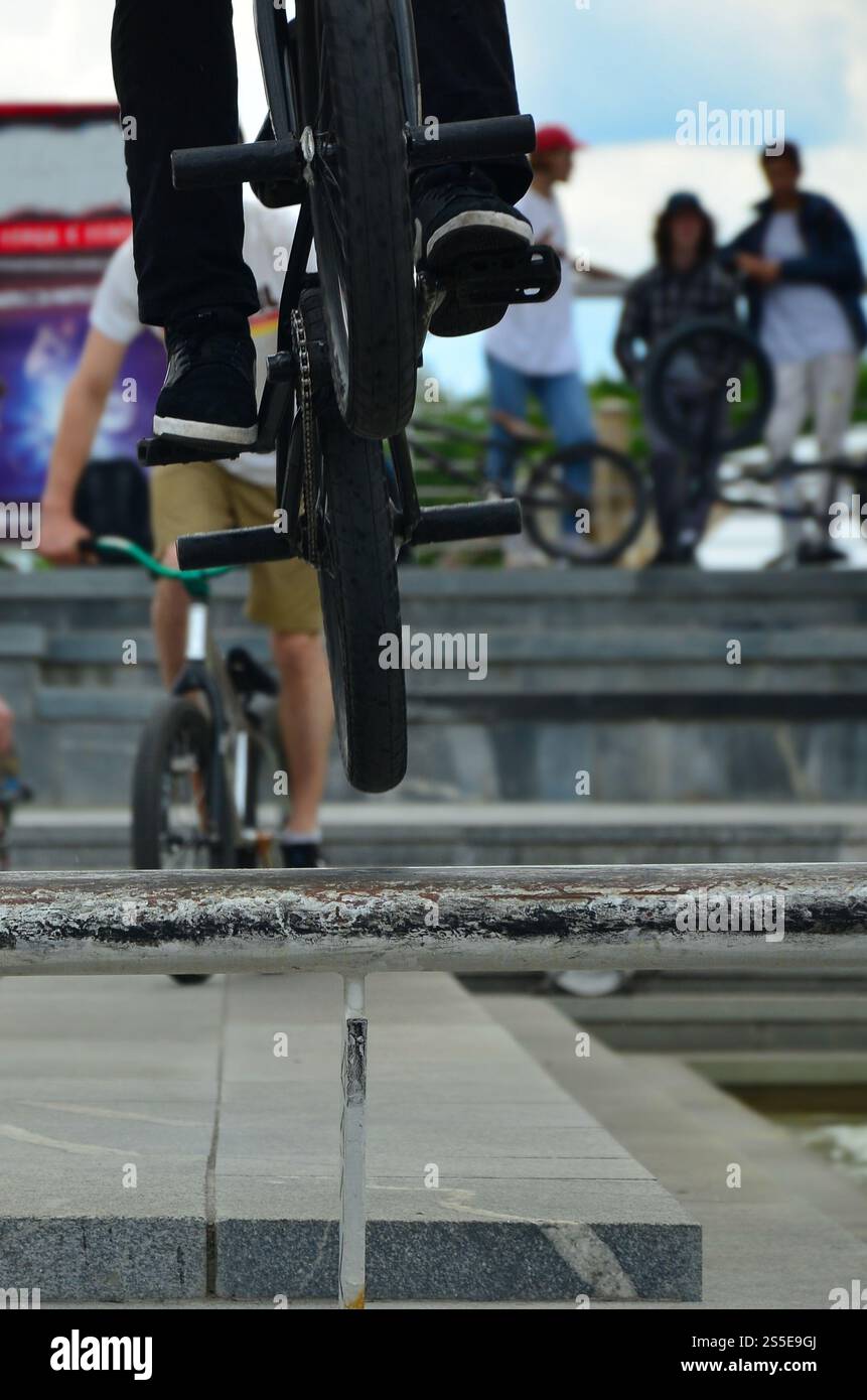 Un cycliste saute par-dessus un tuyau sur un vélo BMX. Beaucoup de gens avec des vélos en arrière-plan. Concept de sports extrêmes Banque D'Images Un cycliste saute par-dessus un tuyau sur un vélo BMX. Beaucoup de gens avec des vélos en arrière-plan. Concept de sports extrêmes Banque D'Images