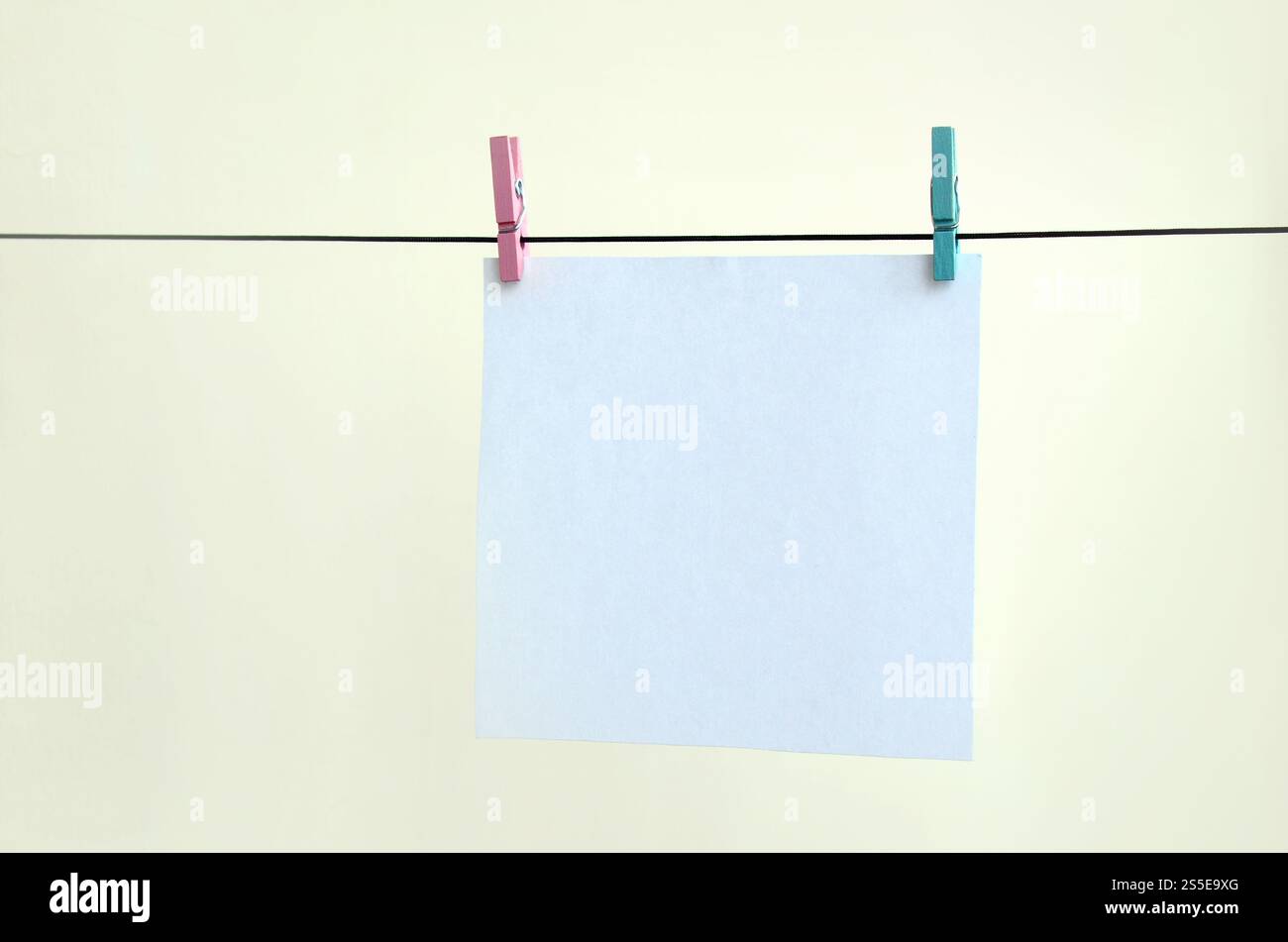 Cartes blanches vierges sur corde, fond de mur clair. Rappel créatif, petites feuilles de papier sur une vieille épinglette, arrière-plan de mémo Banque D'Images