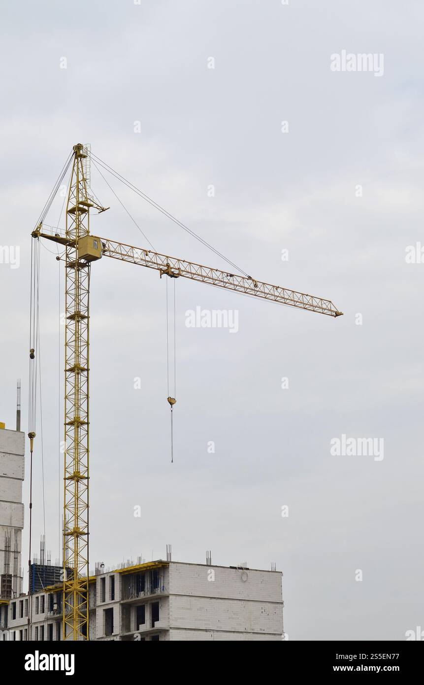 Grues hautes de travail à l'intérieur de l'endroit pour avec des bâtiments hauts en construction contre un ciel bleu clair. Grue et construction progression du travail avec Banque D'Images