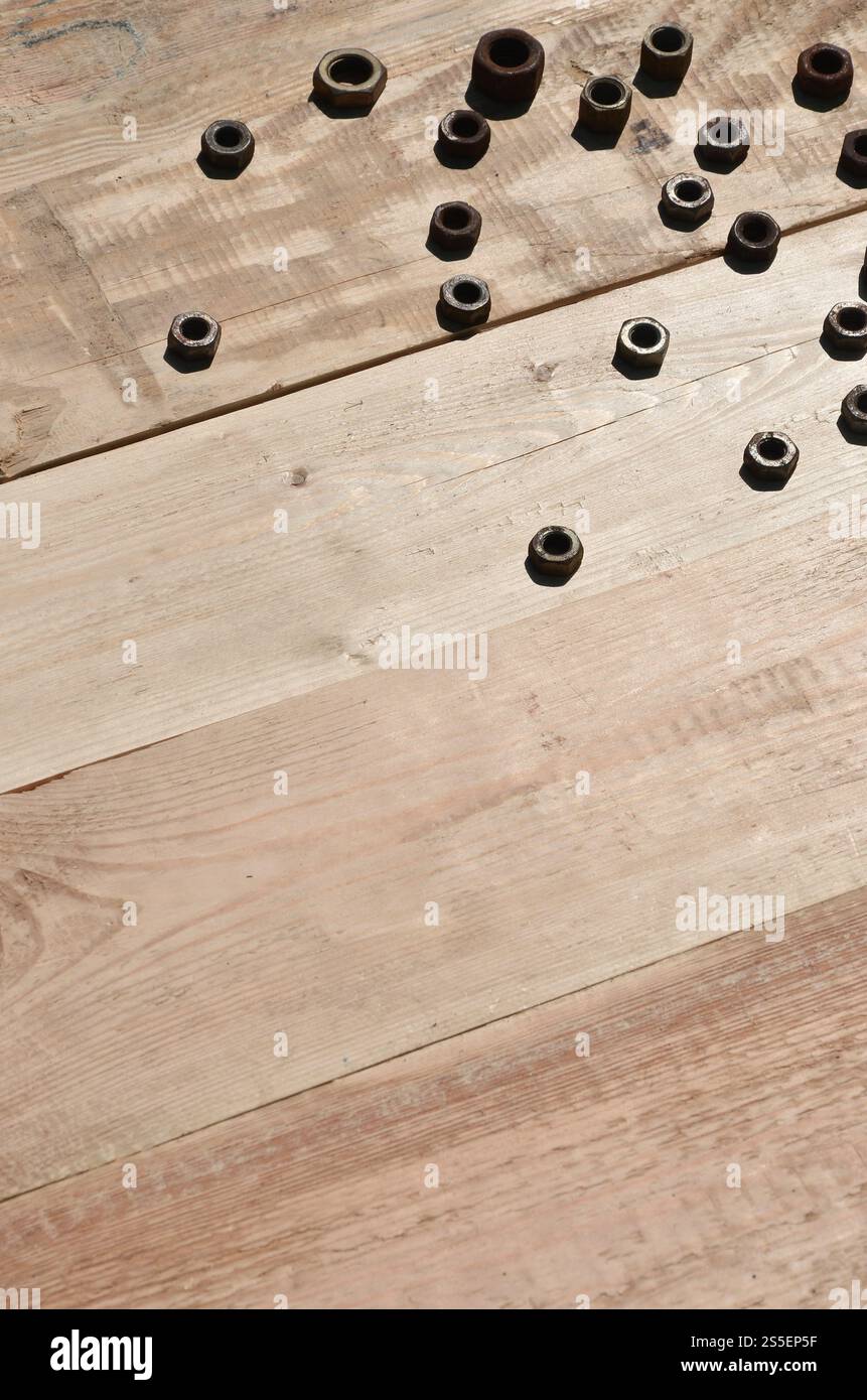 Quelques noix rouillées sur un fond en bois. Des outils ménagers obsolètes en métal rouillé reposent sur une table en bois dans un atelier. Le concept de réparation et Banque D'Images