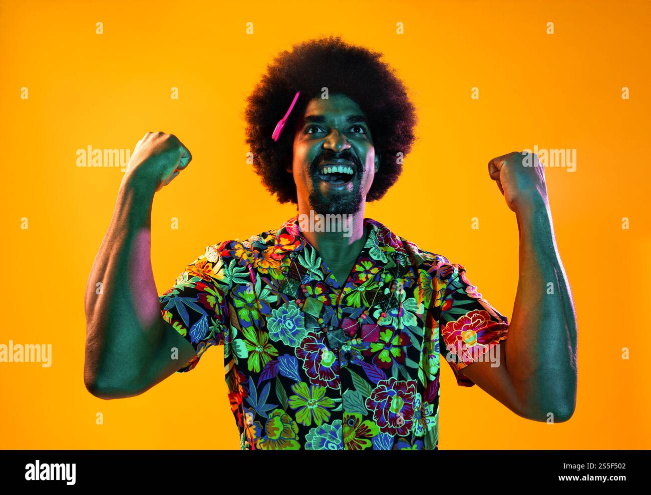 Portrait d'homme africain en studio sur fond coloré - cool noir jeune homme avec tenue élégante posant, éclairage coloré créatif Banque D'Images