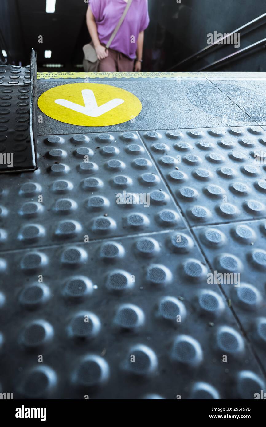 Panneau de direction de flèche jaune sur le sol tactile de la rampe de banlieue de métro Banque D'Images