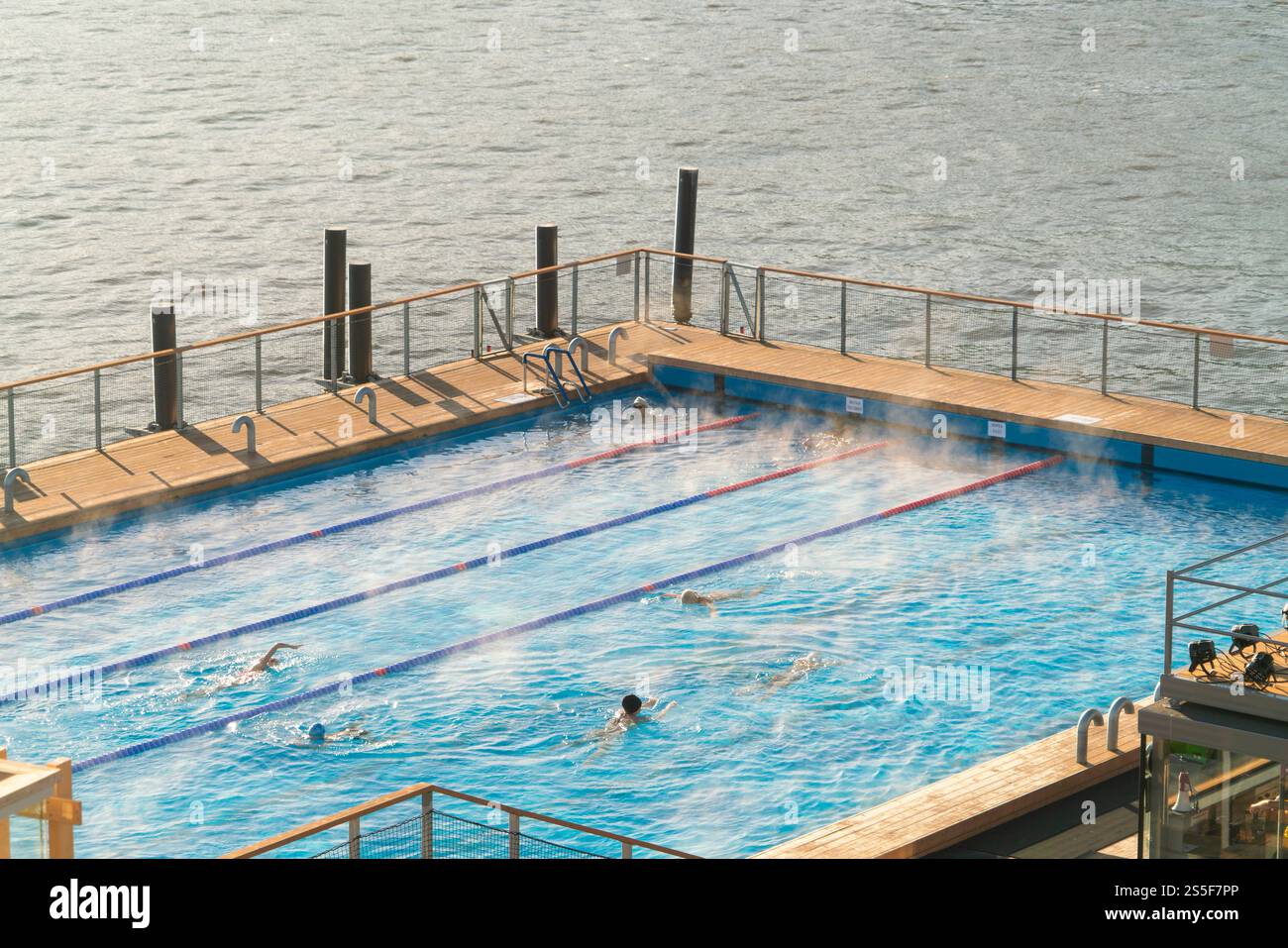Les nageurs apprécient de faire des longueurs dans une piscine extérieure sereine au bord de la mer au coucher du soleil, Helsinki, Finlande Banque D'Images