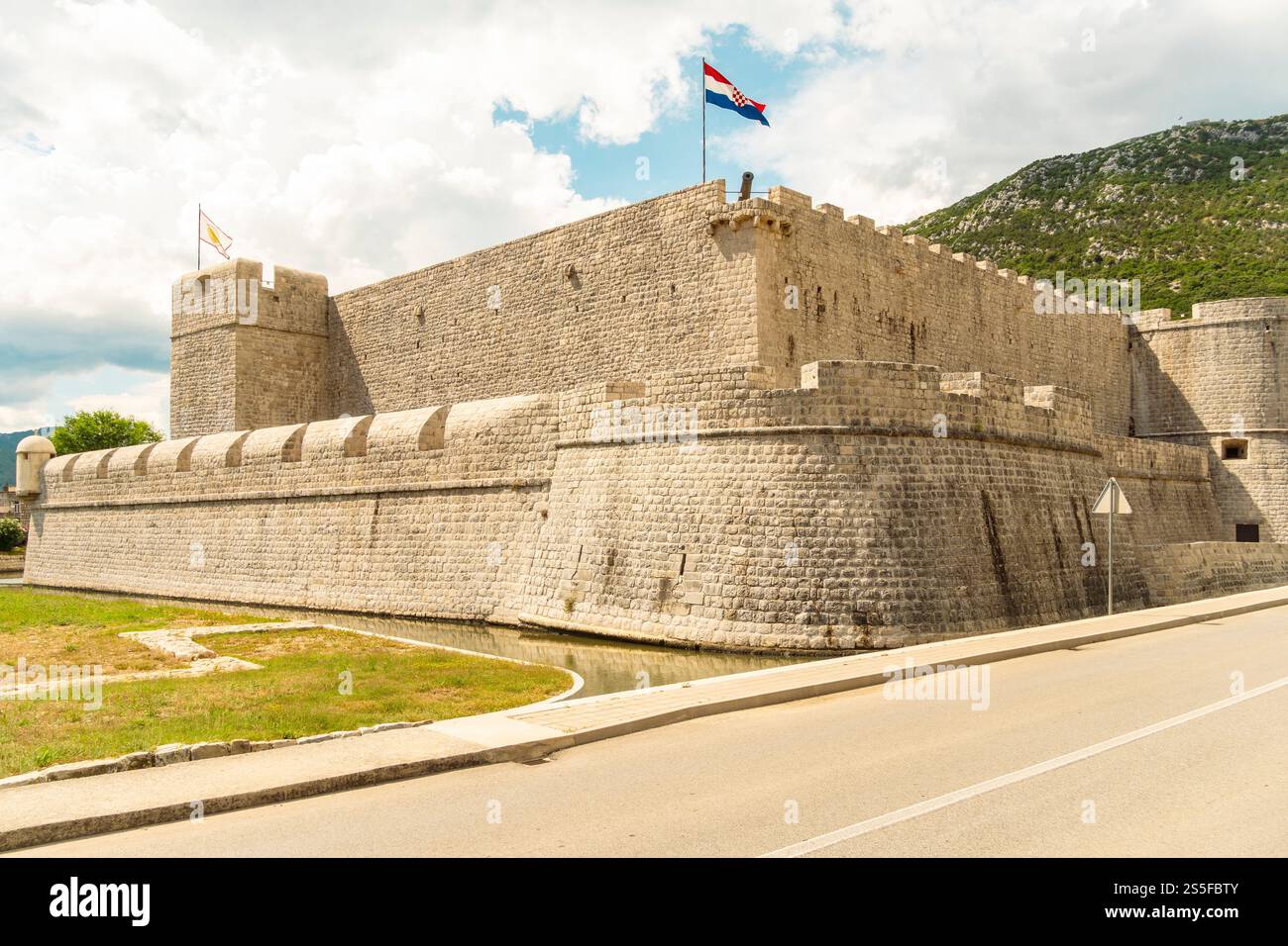 Forteresse en pierre ou fort Kastio avec un drapeau croate volant au-dessus sous un ciel nuageux, Ston, Croatie Banque D'Images