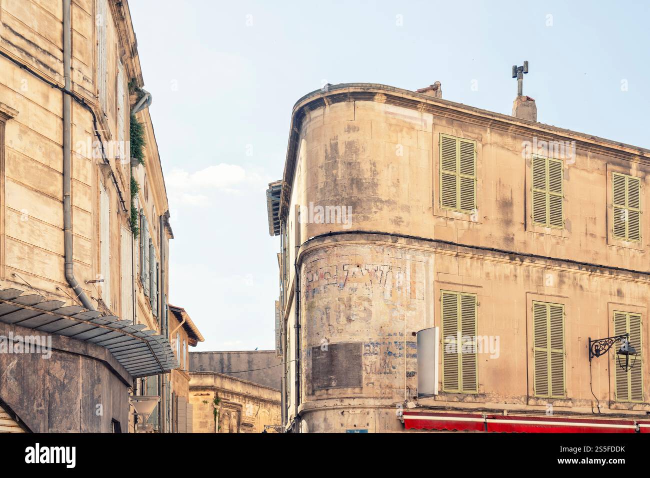 Coin ensoleillé de bâtiments altérés avec vieux signe de graffiti et signes dans un environnement urbain dans la vieille ville d'Arles, Provence, France Banque D'Images