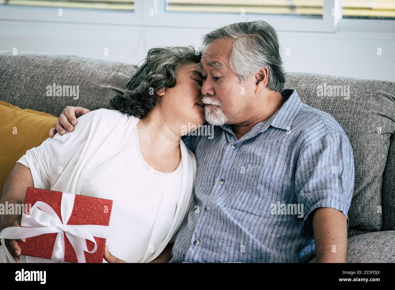 Couples âgés surprise et coffret cadeau au salon Banque D'Images