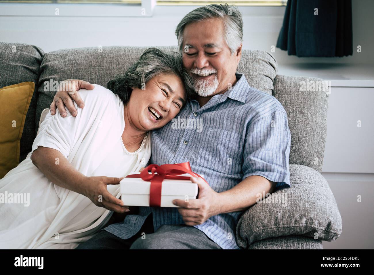 Couples âgés surprise et coffret cadeau au salon Banque D'Images