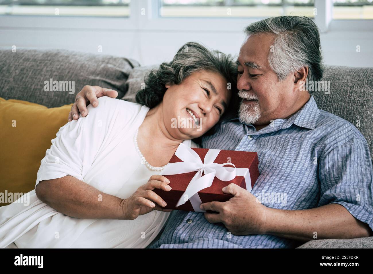Couples âgés surprise et coffret cadeau au salon Banque D'Images