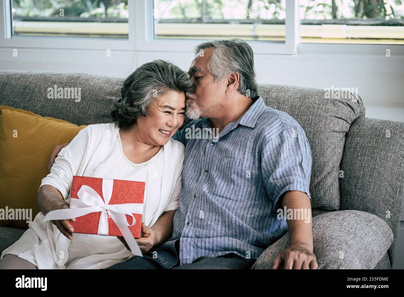 Couples âgés surprise et coffret cadeau au salon Banque D'Images