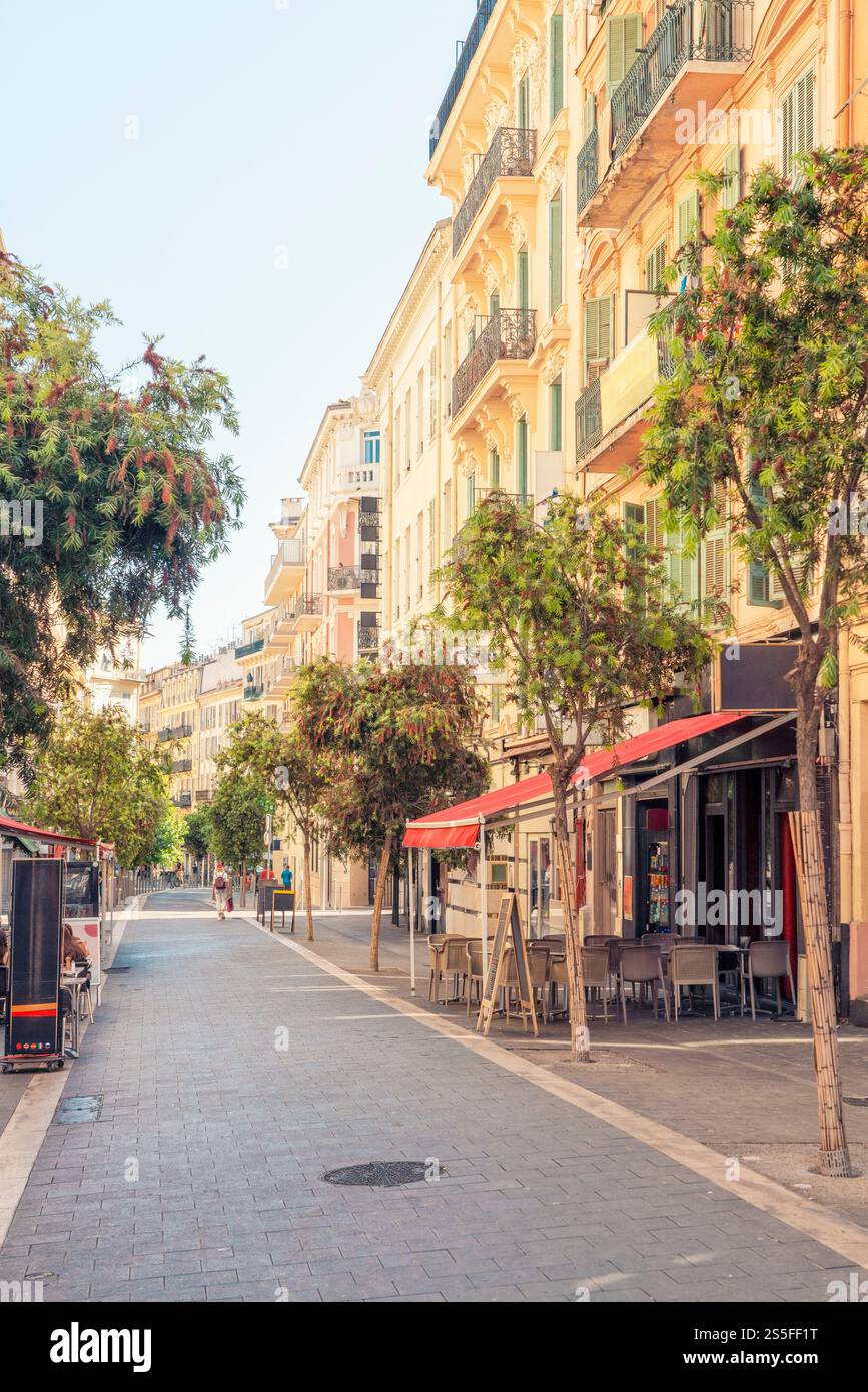 Rue européenne ensoleillée avec des arbres et des sièges de café en plein air à Nice, France Banque D'Images