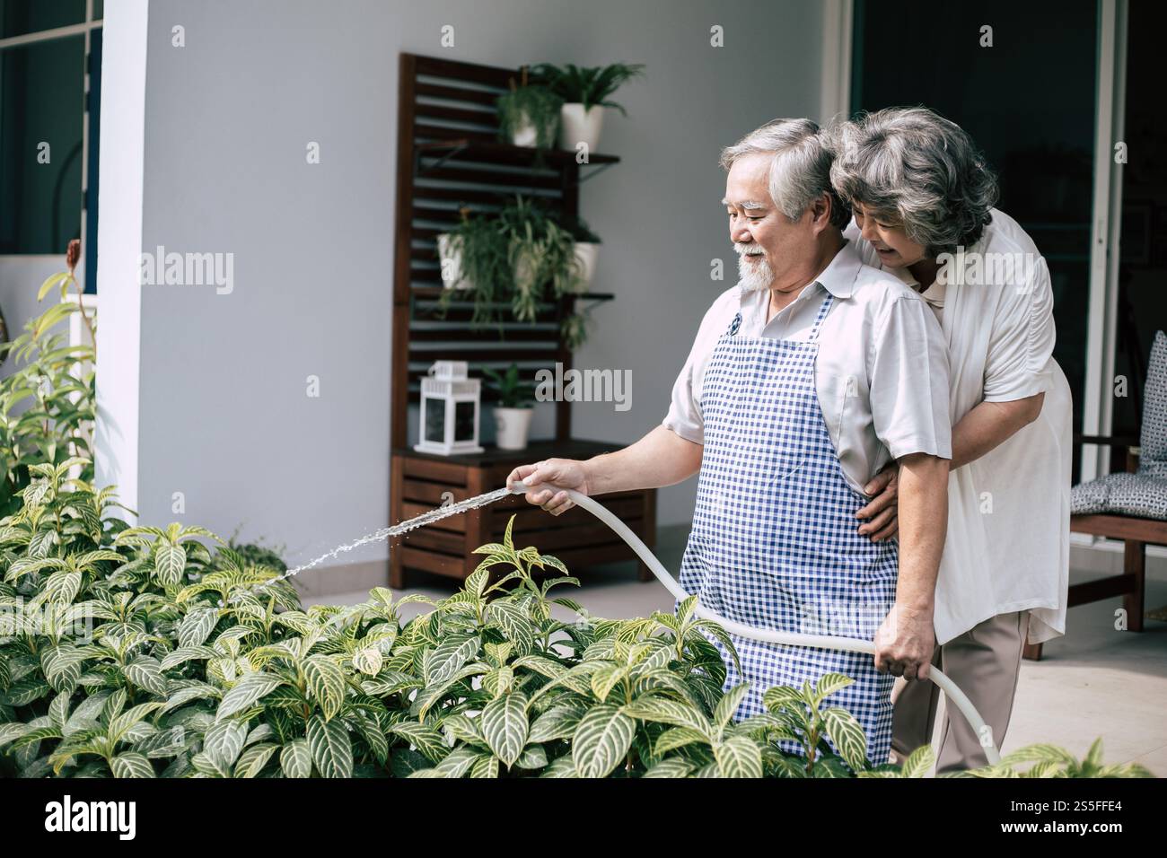 Couple âgé arrosant une fleur dans le jardin de la maison Banque D'Images