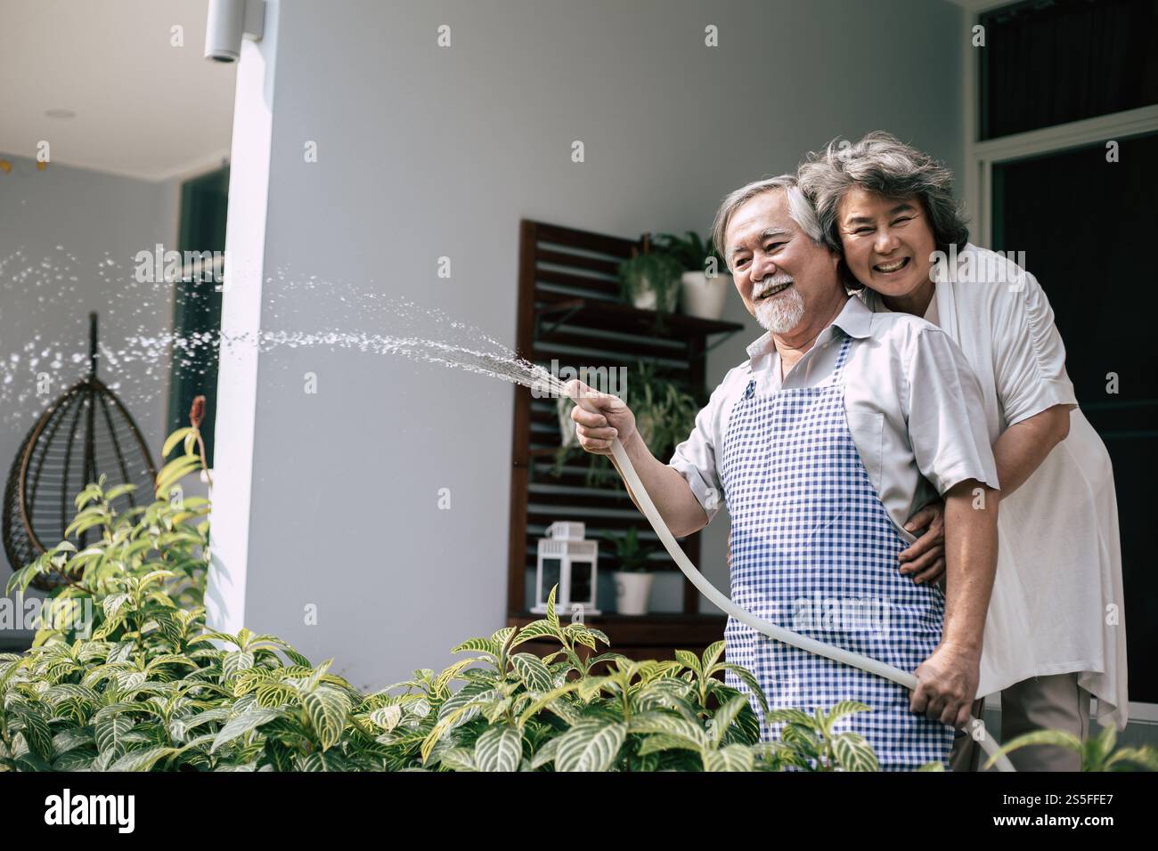 Couple âgé arrosant une fleur dans le jardin de la maison Banque D'Images