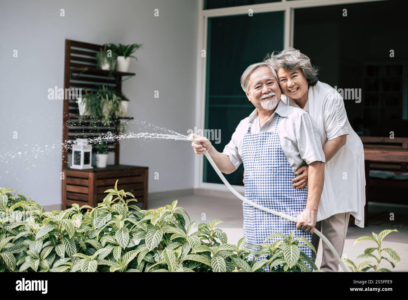 Couple âgé arrosant une fleur dans le jardin de la maison Banque D'Images