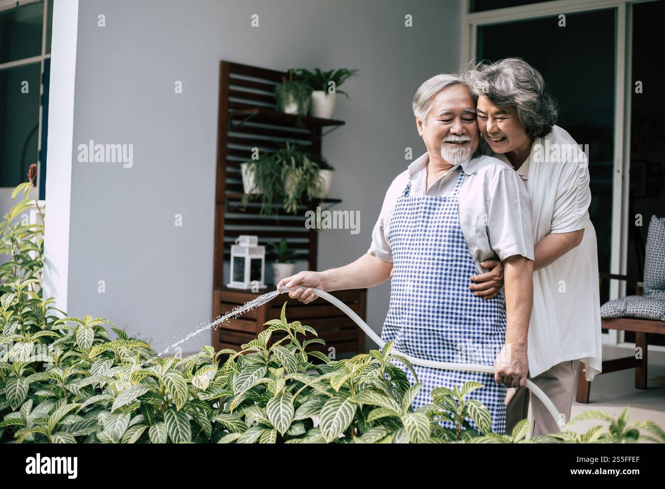 Couple âgé arrosant une fleur dans le jardin de la maison Banque D'Images
