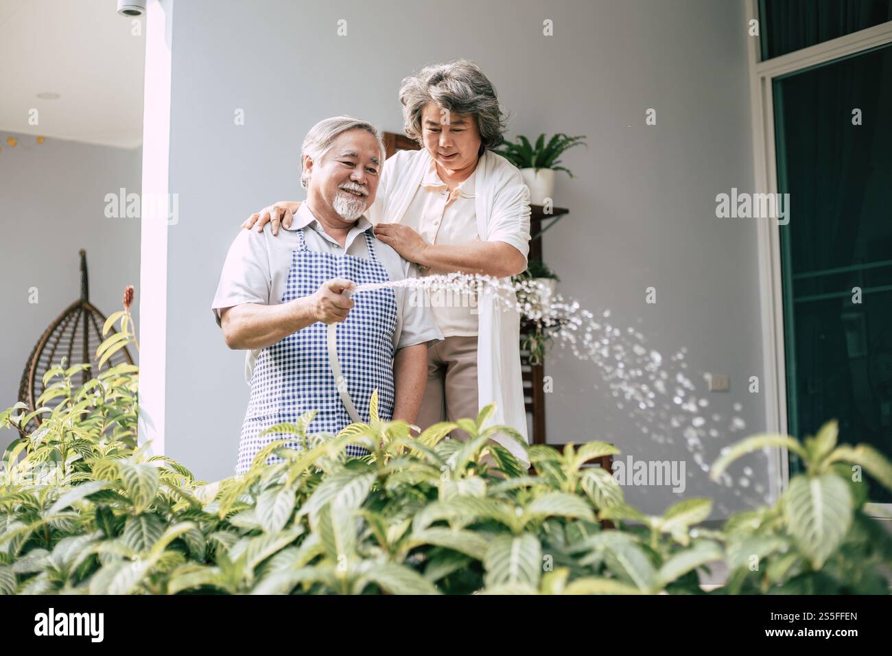 Couple âgé arrosant une fleur dans le jardin de la maison Banque D'Images