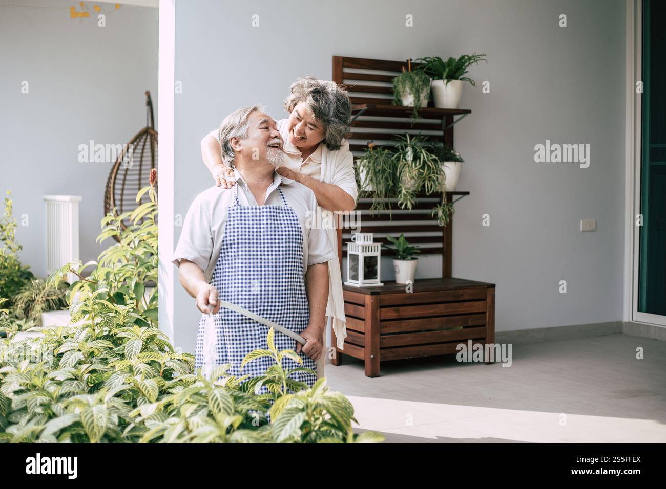 Couple âgé arrosant une fleur dans le jardin de la maison Banque D'Images