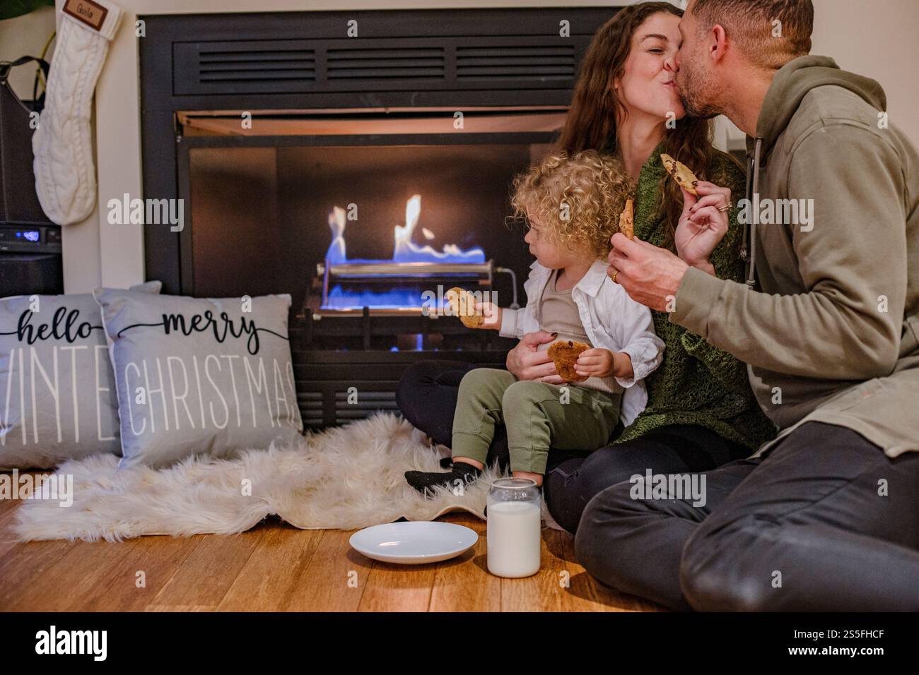 Famille aime les biscuits près de la cheminée avec des décorations de Noël dans un cadre de maison confortable, Ohio, États-Unis Banque D'Images