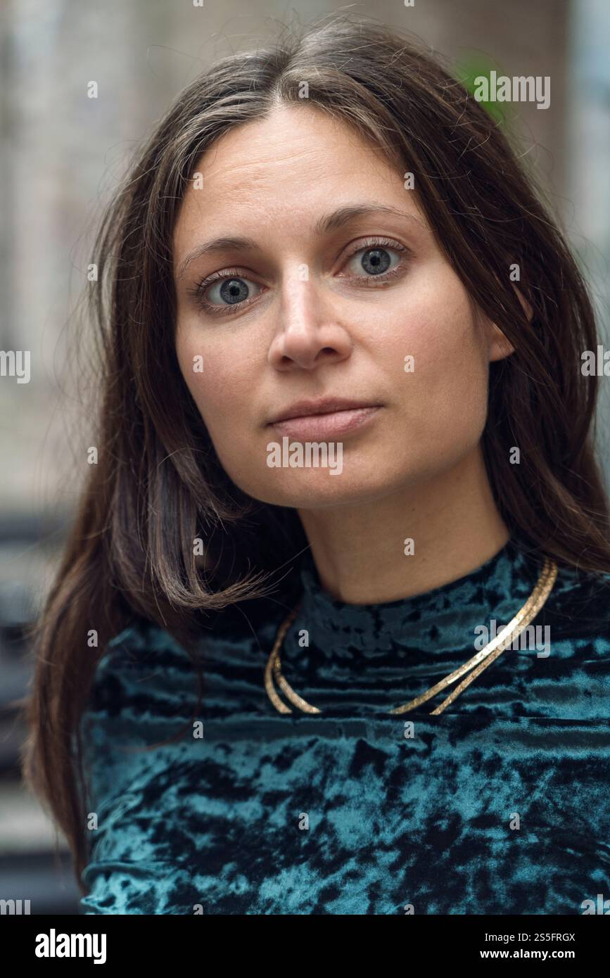 Portrait en gros plan d'une femme aux longs cheveux bruns portant un haut en velours bleu et un collier en or, Berlin, Allemagne Banque D'Images