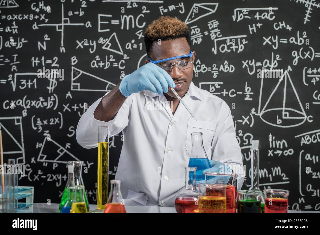 Les scientifiques font tomber des produits chimiques bleu clair dans le verre du laboratoire. Banque D'Images