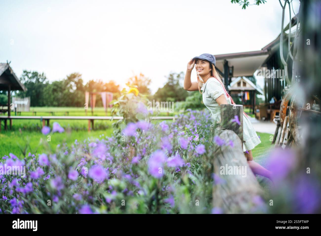 la femme est heureuse de se tenir dans le jardin fleuri dans les rampes en bois. Banque D'Images