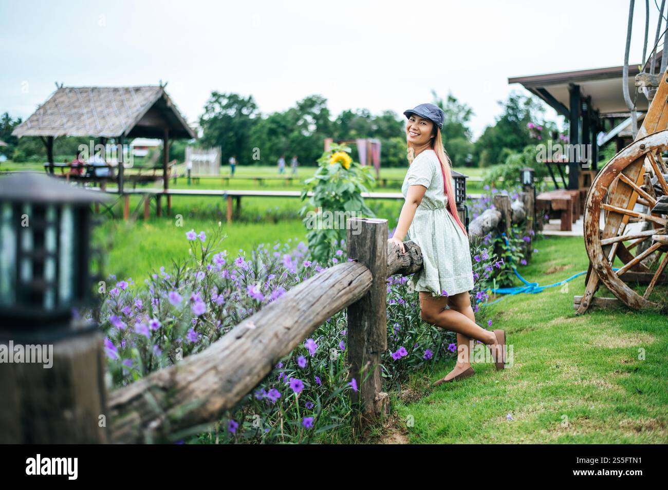 la femme est heureuse de se tenir dans le jardin fleuri dans les rampes en bois. Banque D'Images