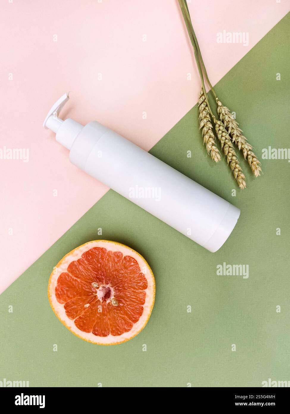 au-dessus de la vue de la bouteille en plastique blanche à pompe vierge, de la moitié de pamplemousse frais et des oreilles séchées naturelles sur fond de papier couleur Banque D'Images