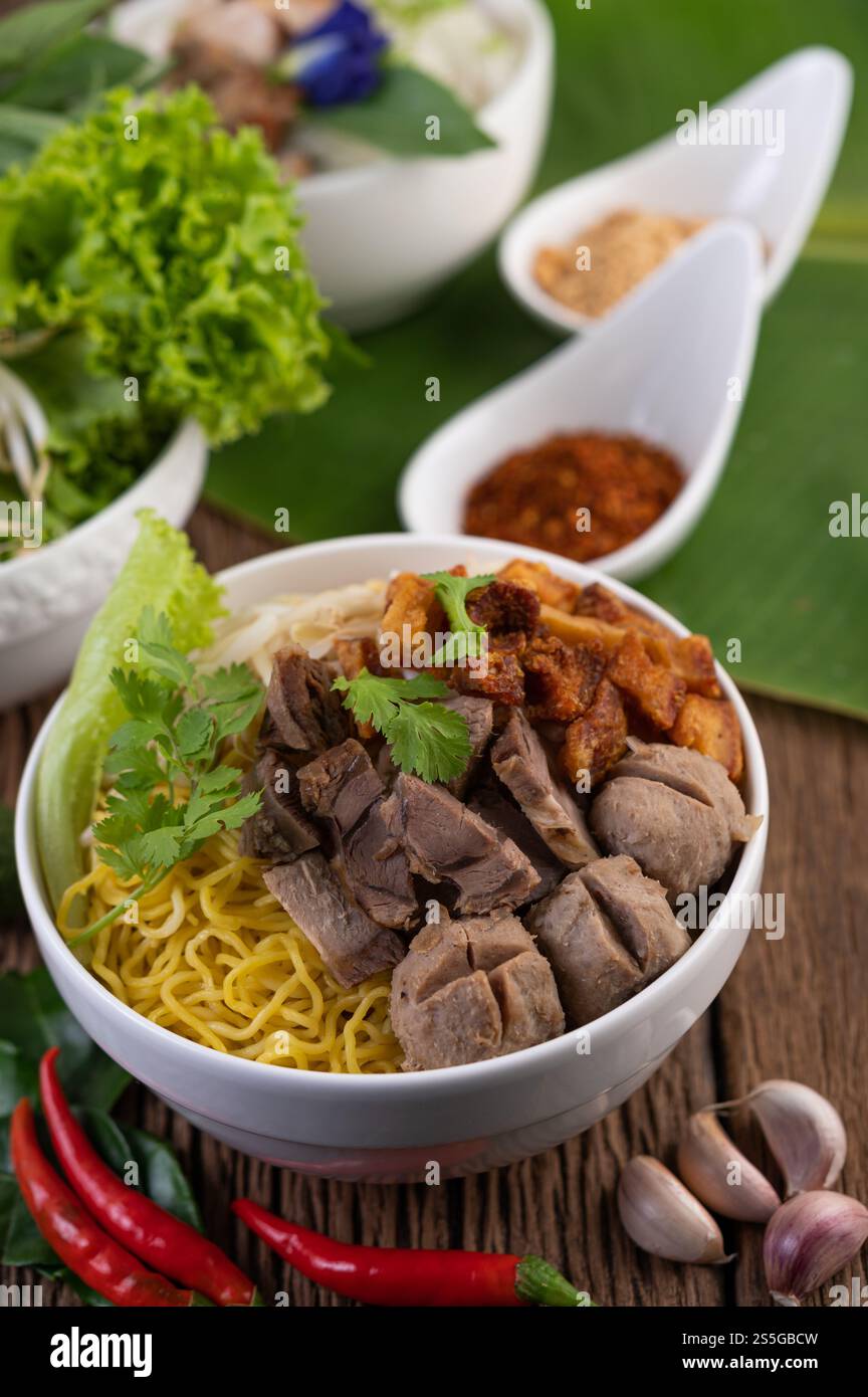 Nouilles jaunes dans une tasse avec du porc croustillant, des tranches de porc et des boulettes de viande avec des nouilles thaïlandaises Banque D'Images