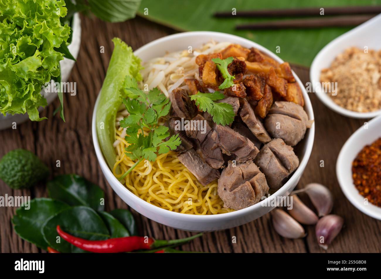 Nouilles jaunes dans une tasse avec du porc croustillant, des tranches de porc et des boulettes de viande avec des nouilles thaïlandaises Banque D'Images