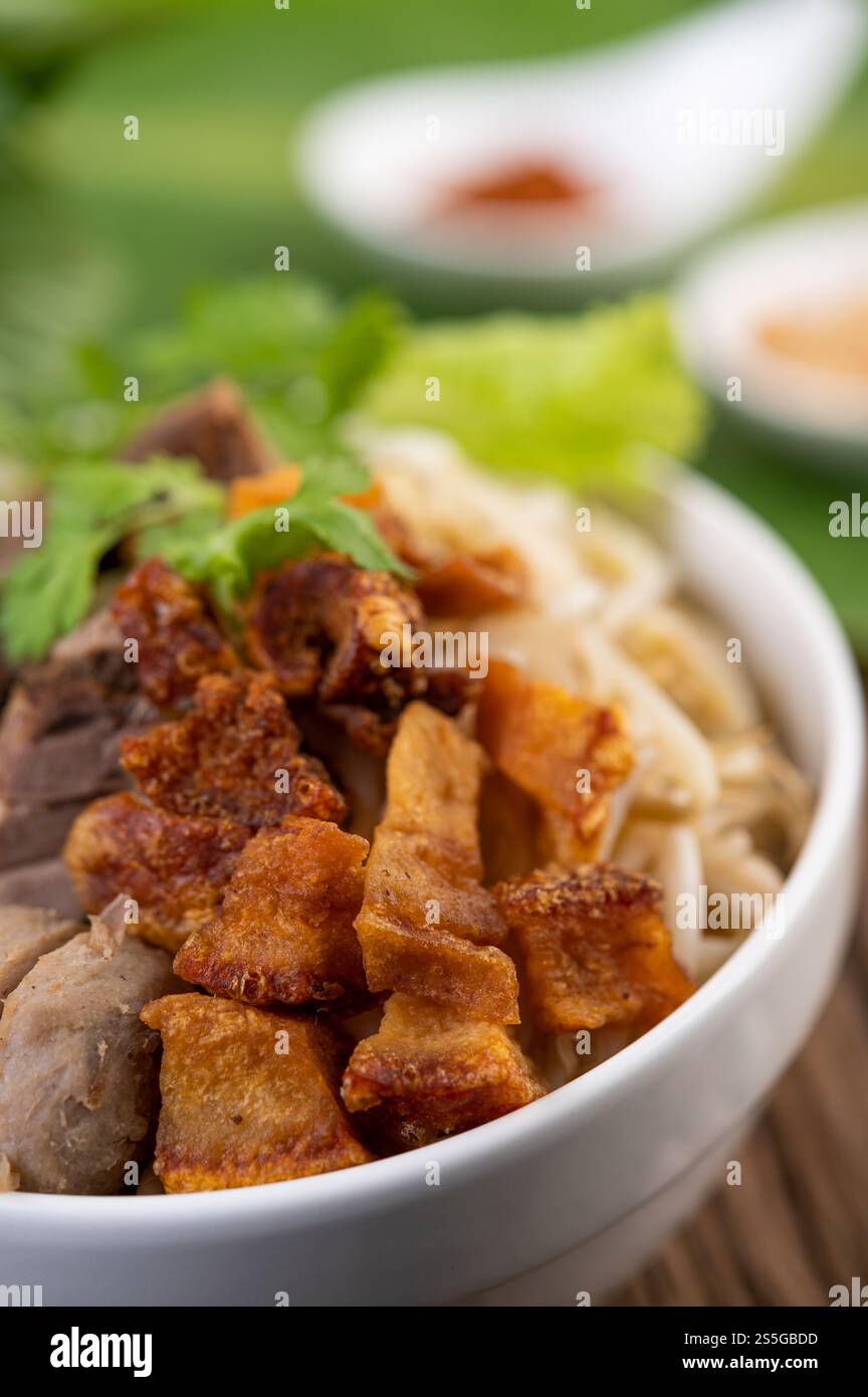 Nouilles jaunes dans une tasse avec du porc croustillant, des tranches de porc et des boulettes de viande avec des nouilles thaïlandaises Banque D'Images