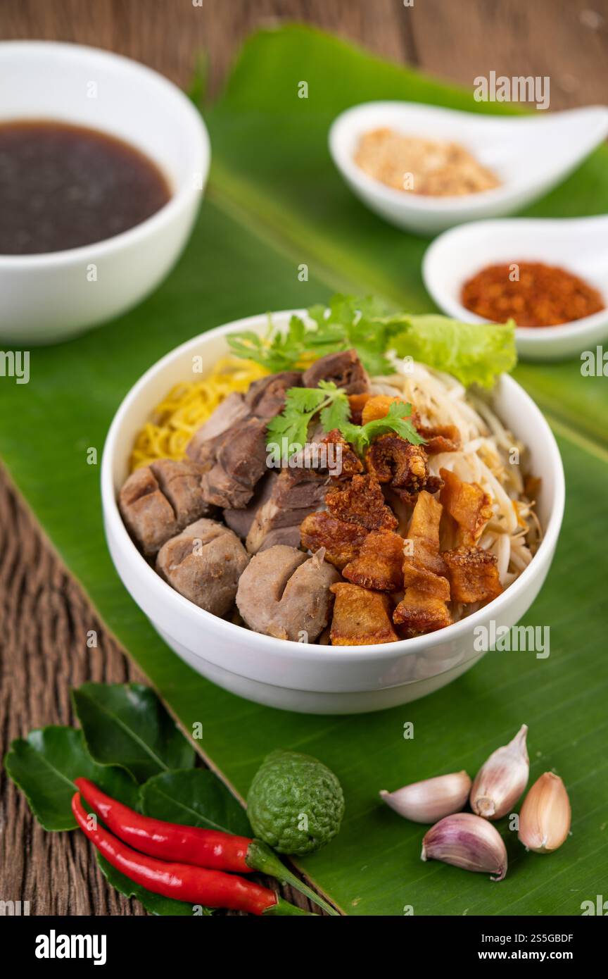 Nouilles jaunes dans une tasse avec du porc croustillant, des tranches de porc et des boulettes de viande avec des nouilles thaïlandaises Banque D'Images