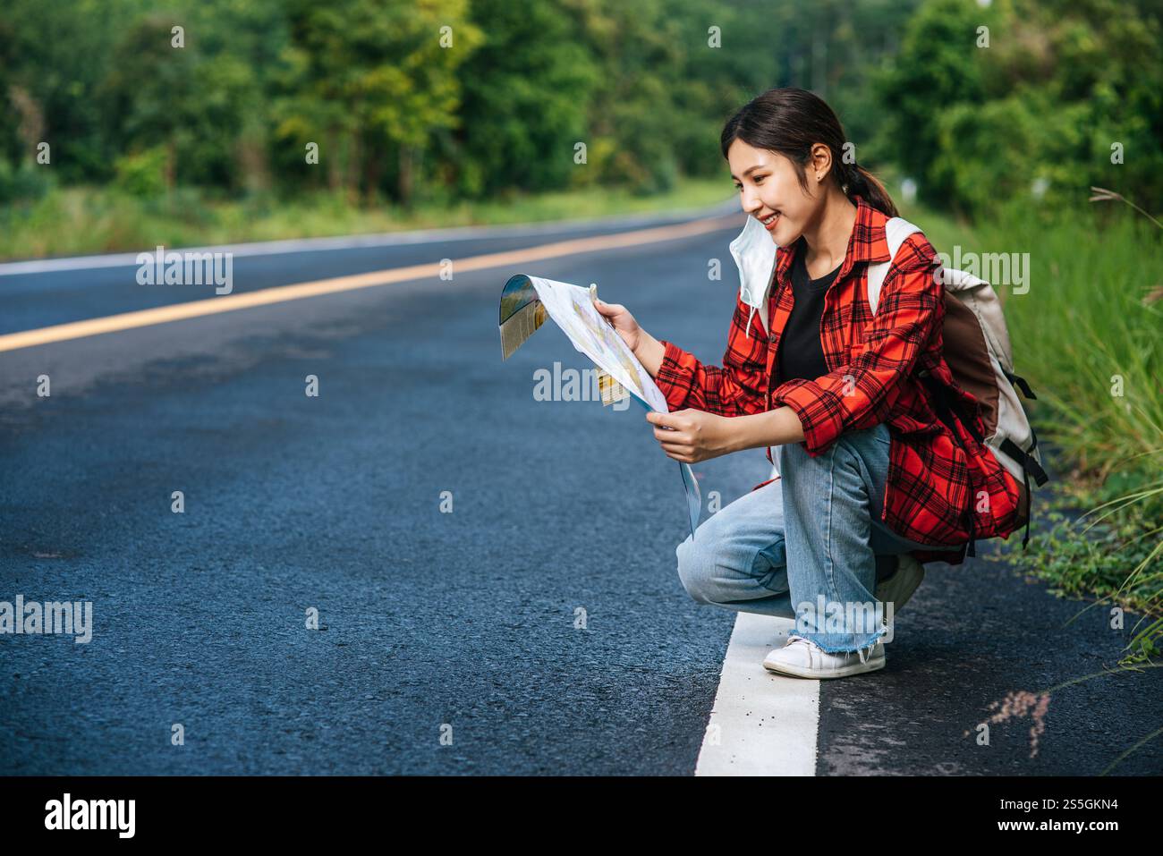 Les touristes féminins s'assoient et regardent la carte sur la route. Banque D'Images