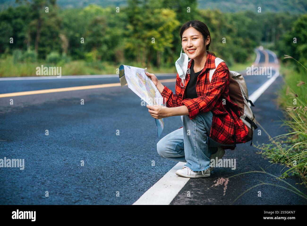Les touristes féminins s'assoient et regardent la carte sur la route. Banque D'Images