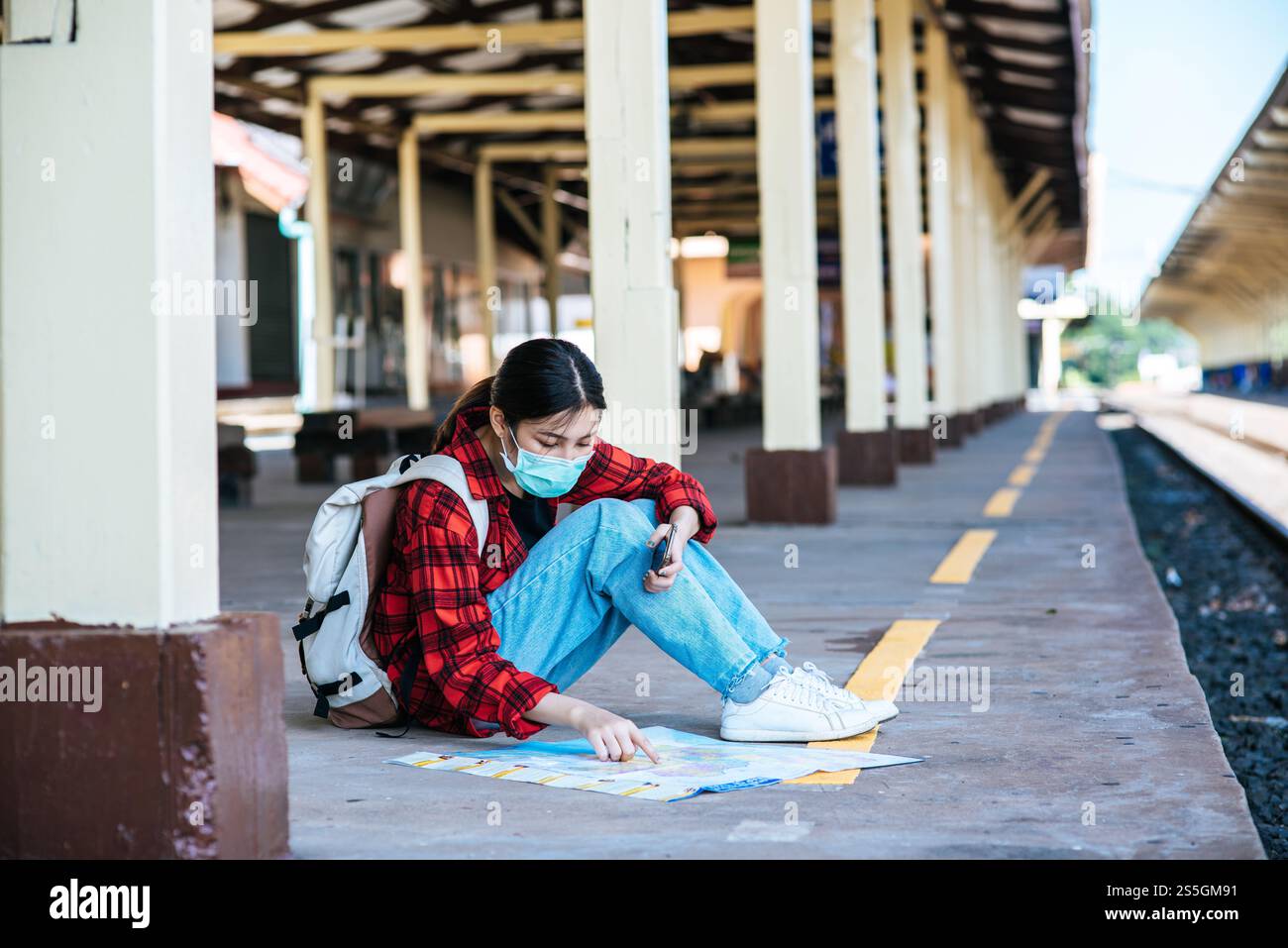 Les touristes féminins s'assoient et regardent la carte sur le sentier à côté du chemin de fer. Banque D'Images