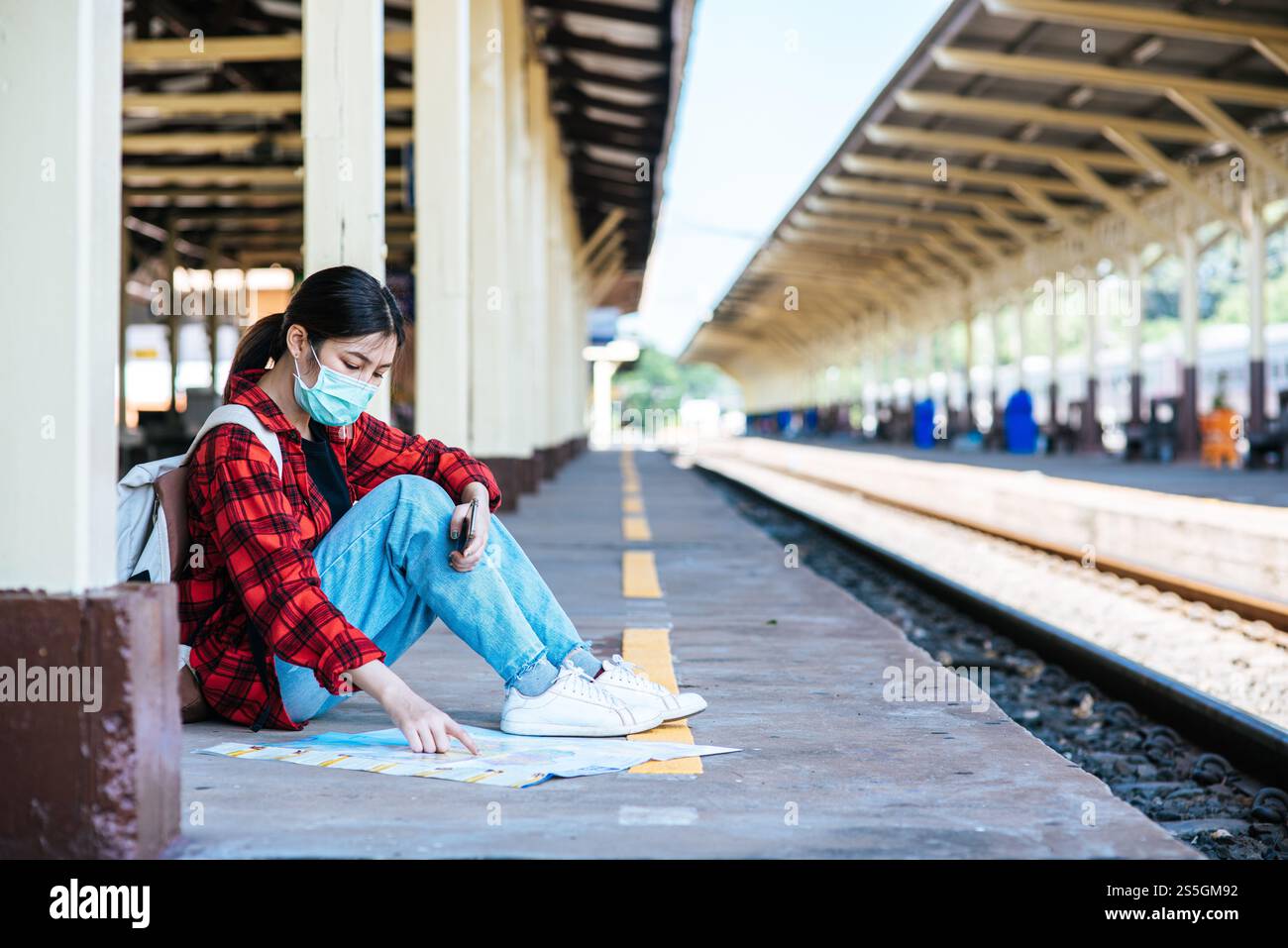 Les touristes féminins s'assoient et regardent la carte sur le sentier à côté du chemin de fer. Banque D'Images