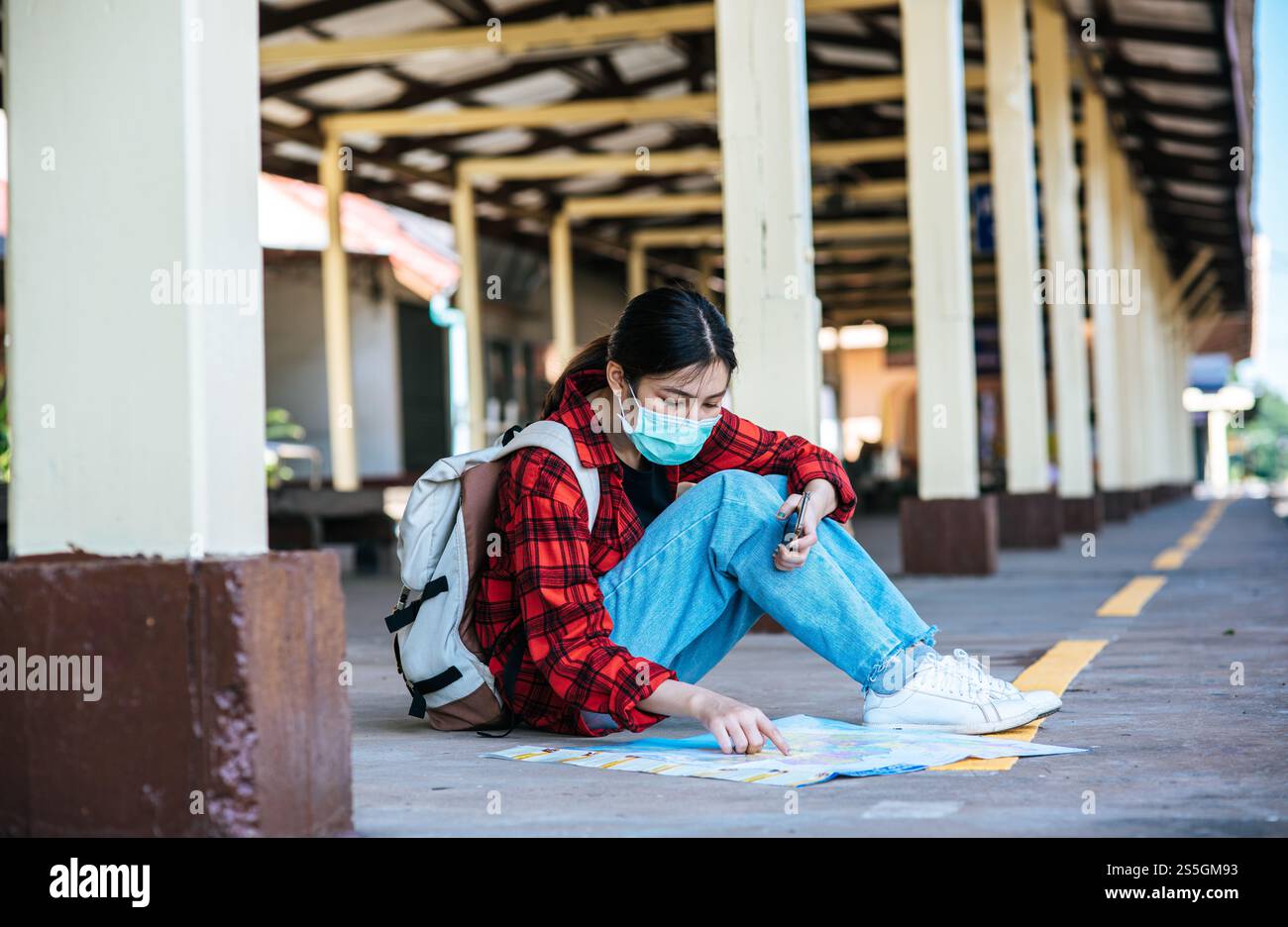 Les touristes féminins s'assoient et regardent la carte sur le sentier à côté du chemin de fer. Banque D'Images